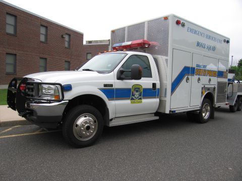 1991 Ford LTD Crown Victoria - white Ford F-series State Police Emergency Services Unit Bomb Squad truck with a utility box body and brush guard parked by a brick buildin…