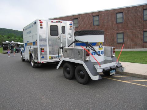 1991 Ford LTD Crown Victoria - Rear view of a State Police Bomb Squad box truck with a tandem-axle trailer carrying a large round containment vessel marked Bomb Squad.