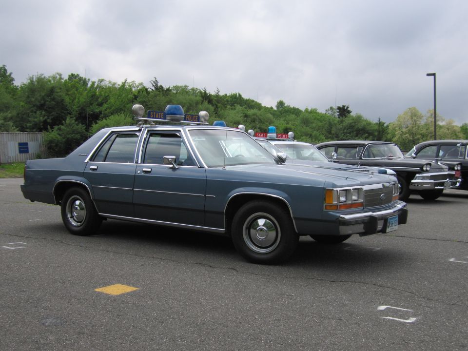 Blue Ford LTD Crown Victoria police sedan with light bar in parking lot