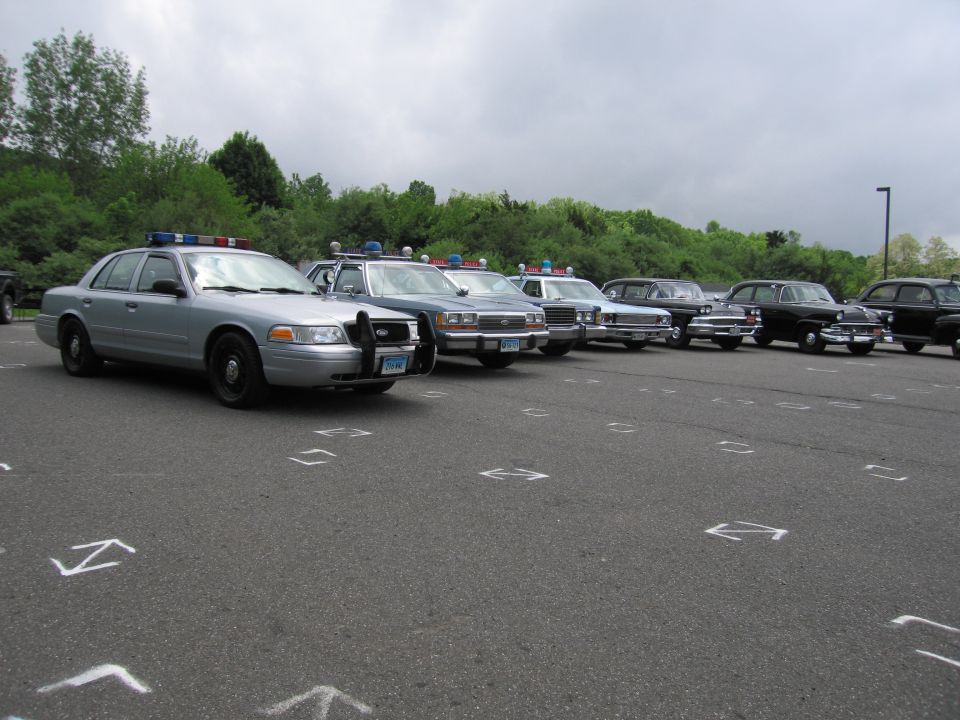 Lineup of silver and dark police sedans parked at an angle in a lot
