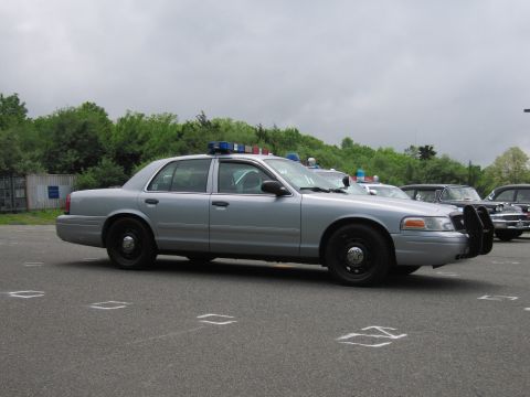 1991 Ford LTD Crown Victoria - silver Ford Crown Victoria police cruiser shown in side profile with roof light bar and front push bumper in a parking lot.