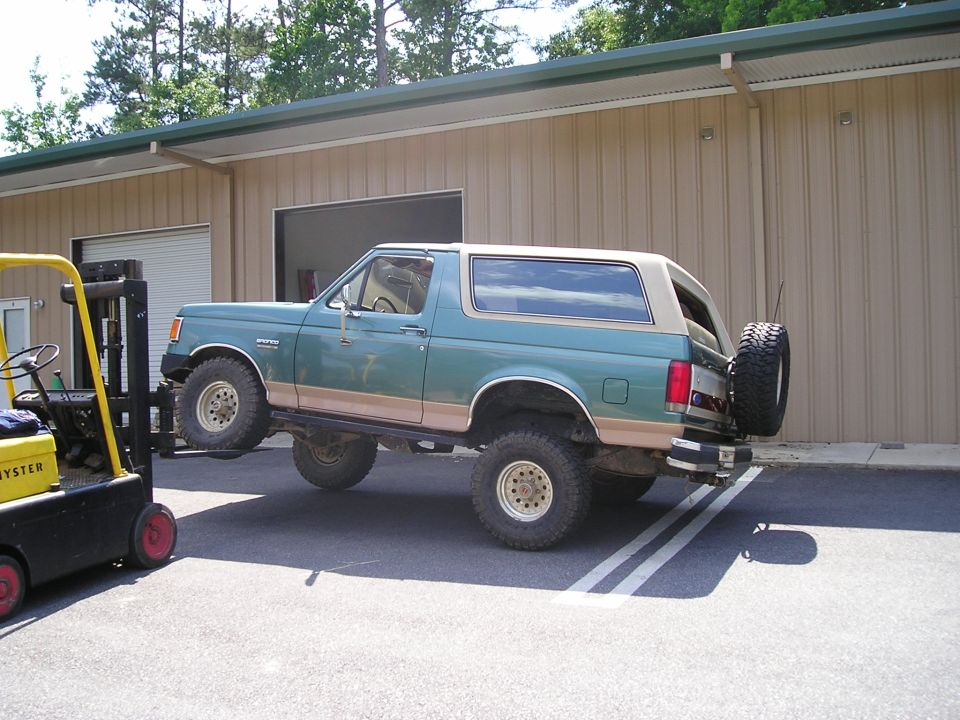 1989 Ford Bronco lifted by a yellow forklift