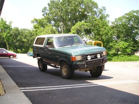 1989 Ford Bronco - This 1989 Ford Bronco is parked in a lot with a red car visible in the distance.