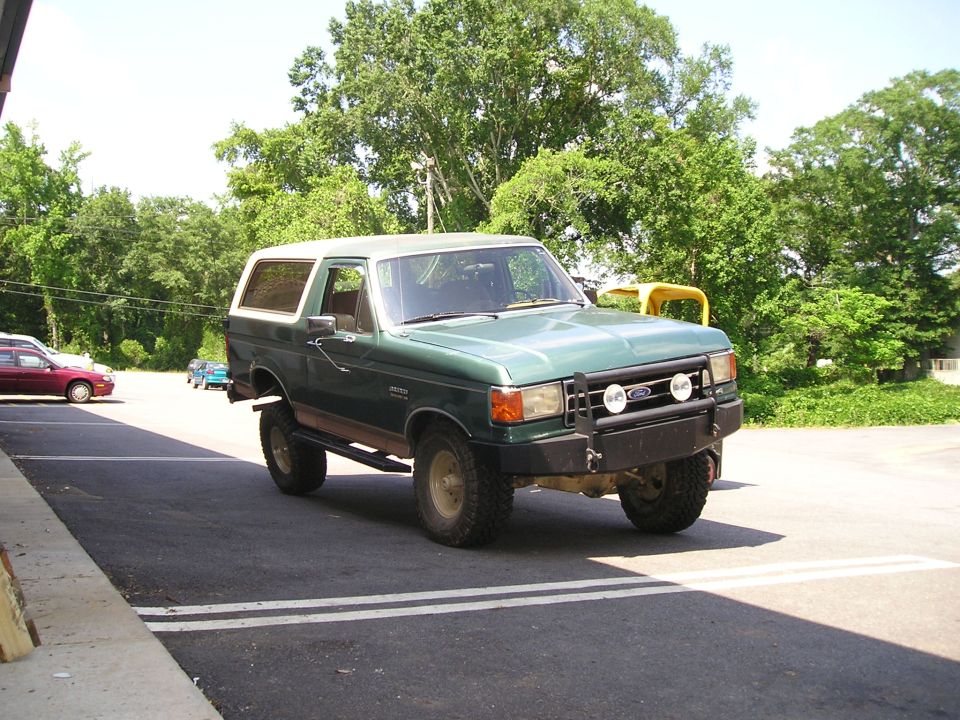 Green and white lifted Ford Bronco, front three-quarter view in parking lot