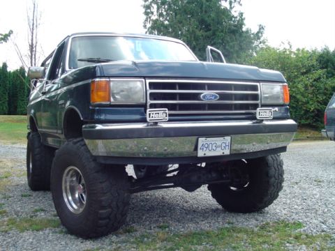 1990 Ford Bronco - This Ford Bronco features a significant lift kit and oversized tires, with Hella auxiliary lights mounted on the bumper.