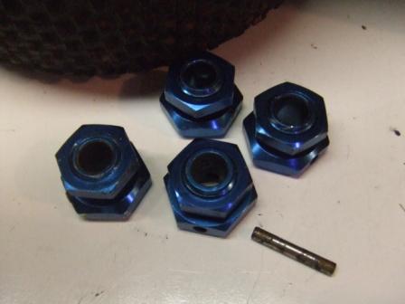 1996 Ford Bronco - Four blue lug nuts and a pin are shown on a flat surface.
