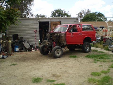 1969 Ford F-250 - This red SUV, likely from the 1980s, is undergoing repairs or modifications with its front end disassembled.