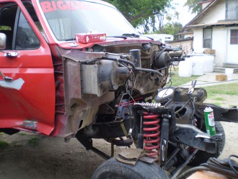 1969 Ford F-250 - Front end of a red truck disassembled, showing the chassis and suspension components.