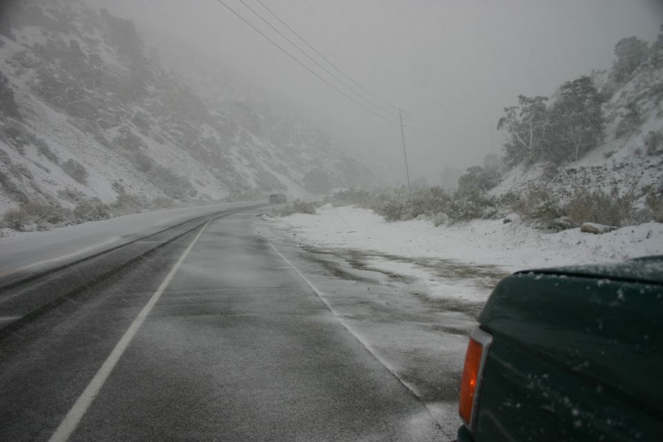 Green SUV rear view on snowy mountain road