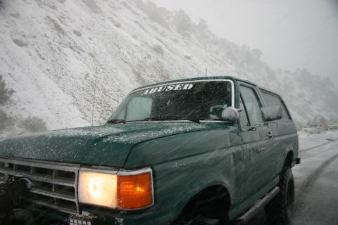 1991 Ford Bronco - 1991 Ford Bronco driving through snowy conditions on a mountain road.
