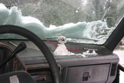 1991 Ford Bronco - A small snowman sits on the dashboard of a 1991 Ford Bronco, with snow covering the windshield.