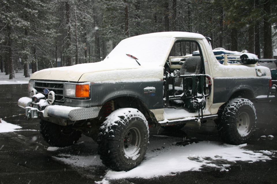 Ford Bronco with aftermarket bumper and lights, covered in snow