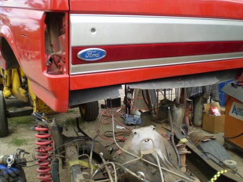 1969 Ford F-250 - A red Ford truck is raised for maintenance, revealing its undercarriage and suspension system.