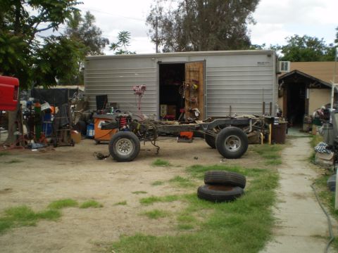 1969 Ford F-250 - A disassembled truck chassis sits in a yard with a garage in the background.