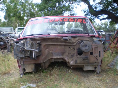 1969 Ford F-250 - Front view of a dismantled red truck with a custom windshield sticker, parked outdoors among other vehicles.