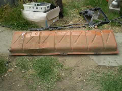 1969 Ford F-250 - An orange metal fuel tank with embossed lines is shown on the ground, with other discarded items in the background.