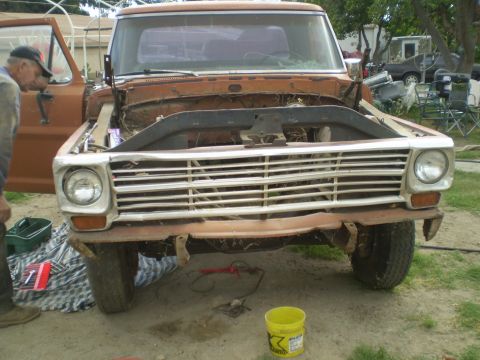 1969 Ford F-250 - Front view of a 1967 Ford F-Series truck, hood open, with a person inspecting the engine bay.