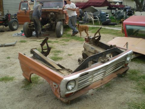 1969 Ford F-250 - A disassembled truck front end sits on the ground, with a partially dismantled truck in the background.