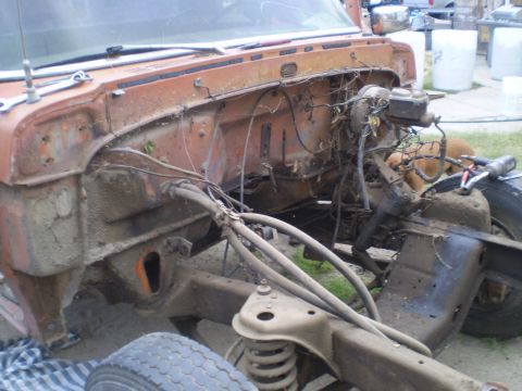 1969 Ford F-250 - The engine bay of a truck is shown disassembled, revealing the chassis and suspension parts. A dog is in the background.