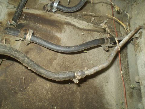 1969 Ford F-250 - Hoses and metal tubing are visible, secured with clamps, in a dirty vehicle compartment.