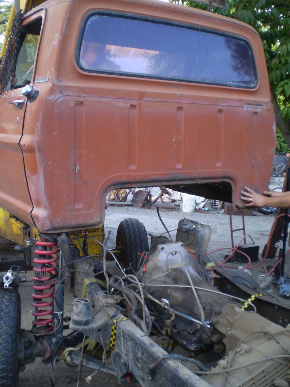 Orange pickup truck cab and chassis undergoing repair, viewed from the side