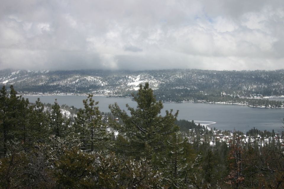 Snowy landscape with a lake and trees, overcast sky, Supermotors logo in lower right