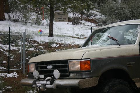 1991 Ford Bronco - A two-tone Ford Bronco is parked in a snowy landscape with a sign that reads 'End of the Road'.