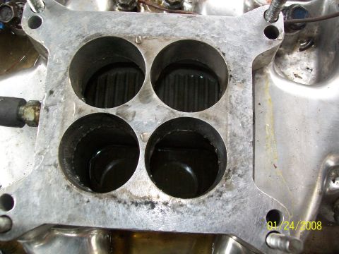 1972 Ford Ranchero - A close-up view of a carburetor intake manifold, showing four circular openings and signs of wear and tear.