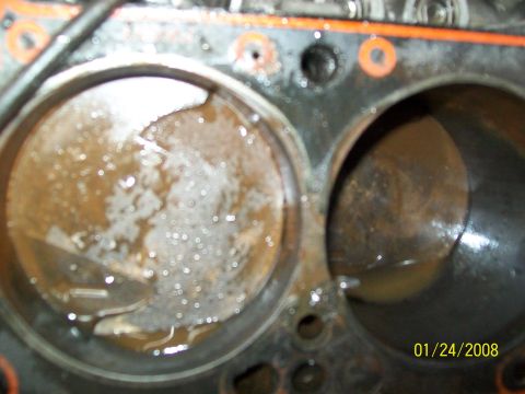 1972 Ford Ranchero - Close-up view of engine cylinders showing fluid and rust, indicating potential internal damage.