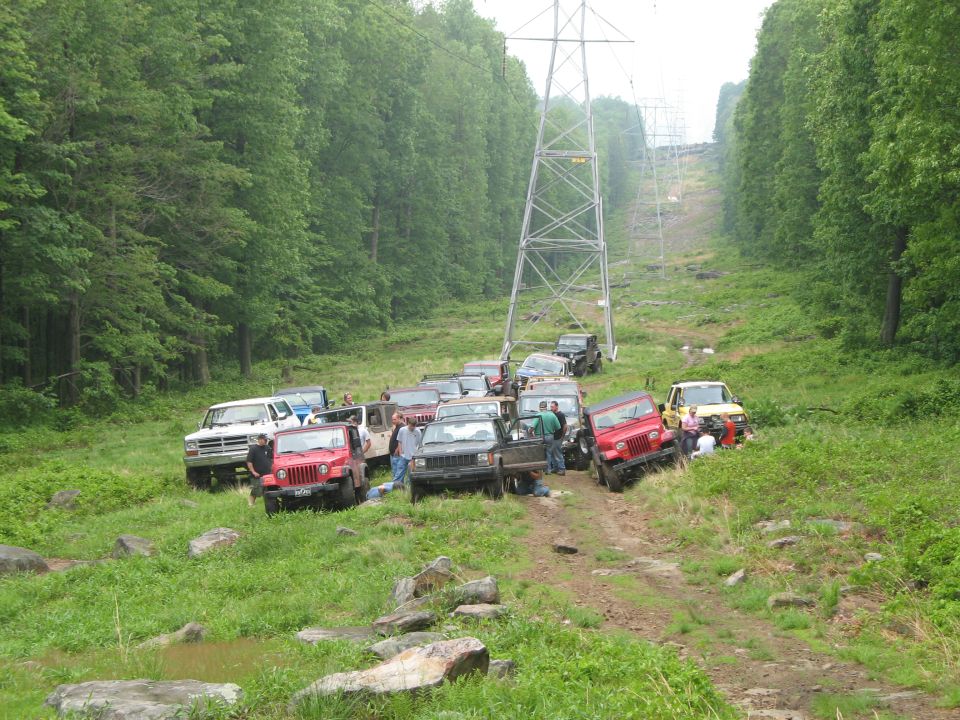 Off-road vehicles gathered on a dirt path near power lines