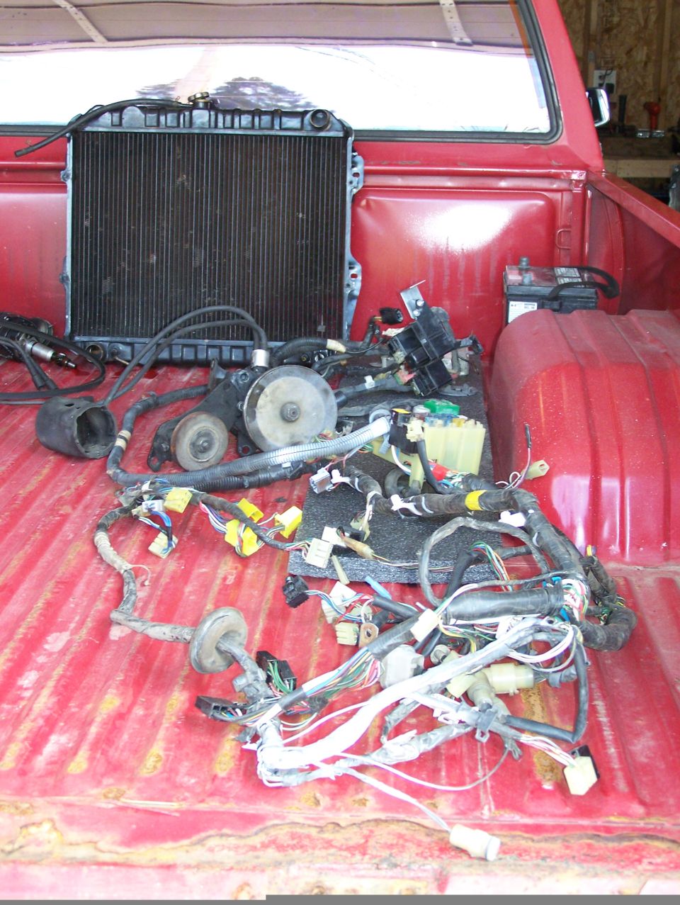 Radiator and tangled wiring harness in the bed of a red pickup truck