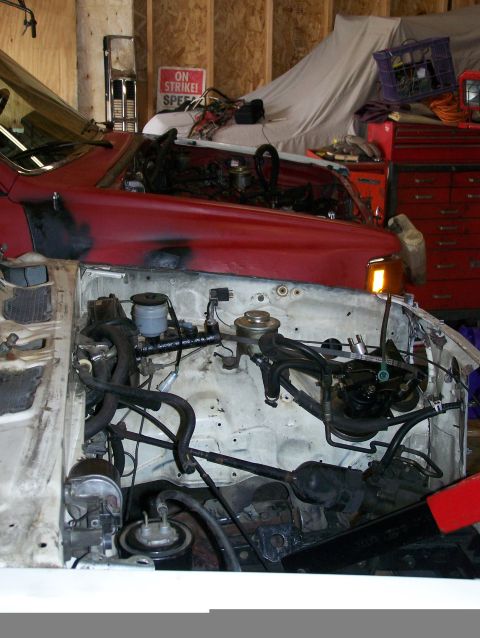 1988 Suzuki Samurai - Engine bay of a vehicle undergoing repairs, showing various hoses and mechanical parts.