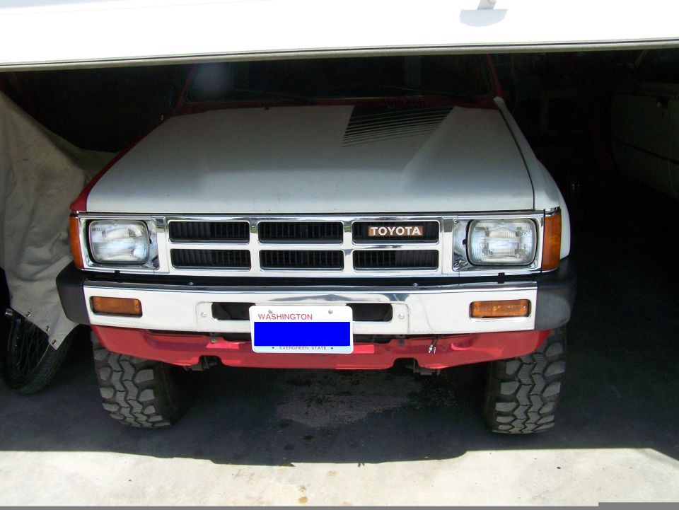 Toyota pickup truck front view, red bumper, gray hood with black stripes, Washington license plate