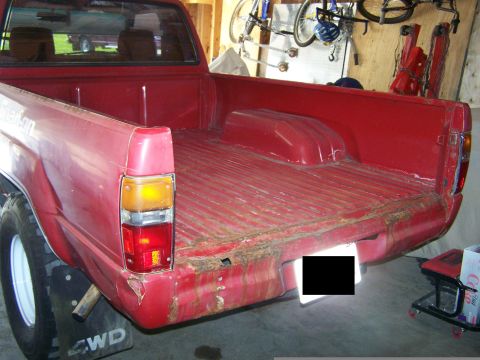 1988 Suzuki Samurai - This red pickup truck's bed shows signs of wear and tear, with rust visible on the rear bumper.