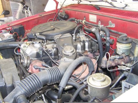 1988 Suzuki Samurai - Close-up view of an engine bay, showing various hoses, the engine block, and other mechanical components.
