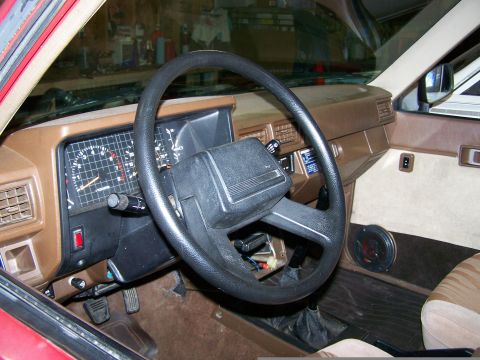 1988 Suzuki Samurai - The interior of a 1988 Suzuki Samurai, a brown dashboard and beige door panels.