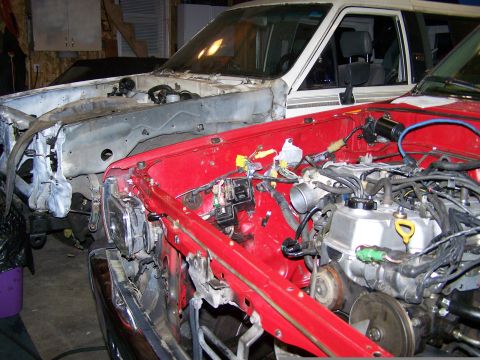1988 Suzuki Samurai - Two trucks are in a garage, with their front ends disassembled for repair or modification.