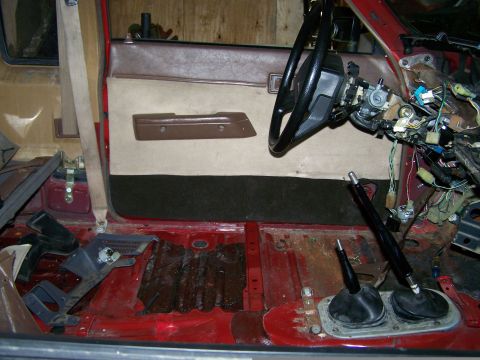 1988 Suzuki Samurai - The interior of a red vehicle shows exposed wiring and a disassembled dashboard, with two prominent gear shifters.
