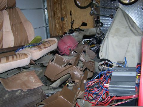 1988 Suzuki Samurai - Interior parts and wiring are piled up, obscuring the main subject in this garage scene.