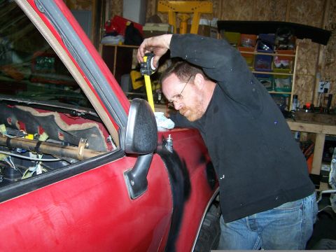 1988 Suzuki Samurai - A man uses a tape measure on the side of a red vehicle, possibly during a repair or modification.