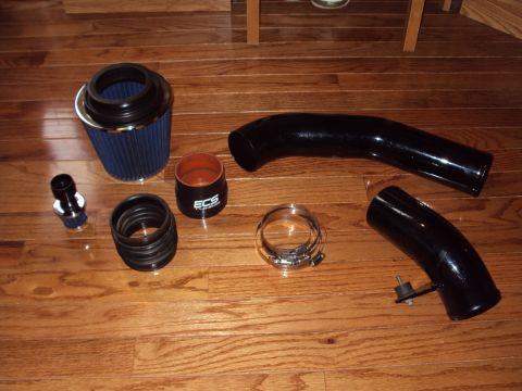 1993 Ford Probe - Performance intake components, including a blue cone air filter and black tubing, are laid out on a wooden surface.