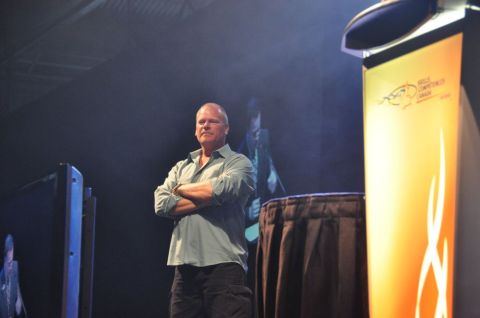 1996 Ford Bronco - A man stands on a stage with his arms crossed, facing an audience.