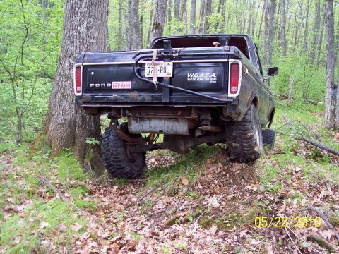 1979 Ford Bronco - A black 1979 Ford Bronco is parked at an angle in a forest, with its rear facing the camera.