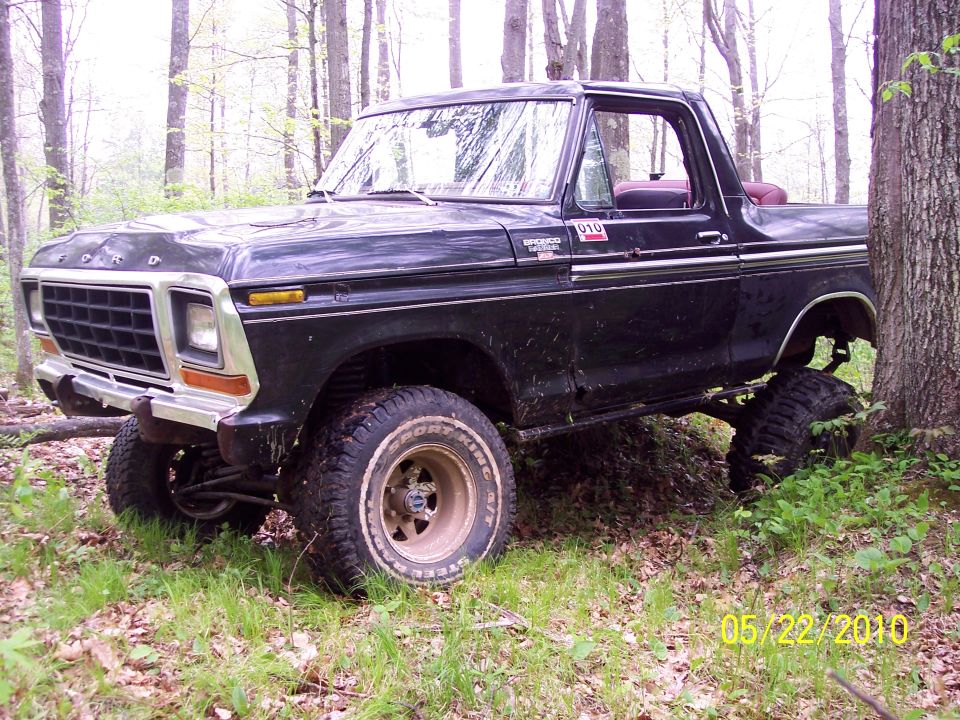 Black 1978 Ford Bronco with lifted suspension parked in a wooded area