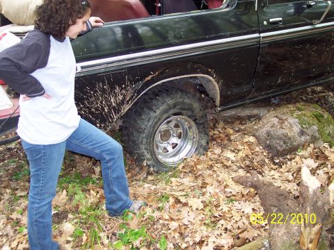 1979 Ford Bronco - Muddy 1978 Ford Bronco is stuck off-road with a woman observing.