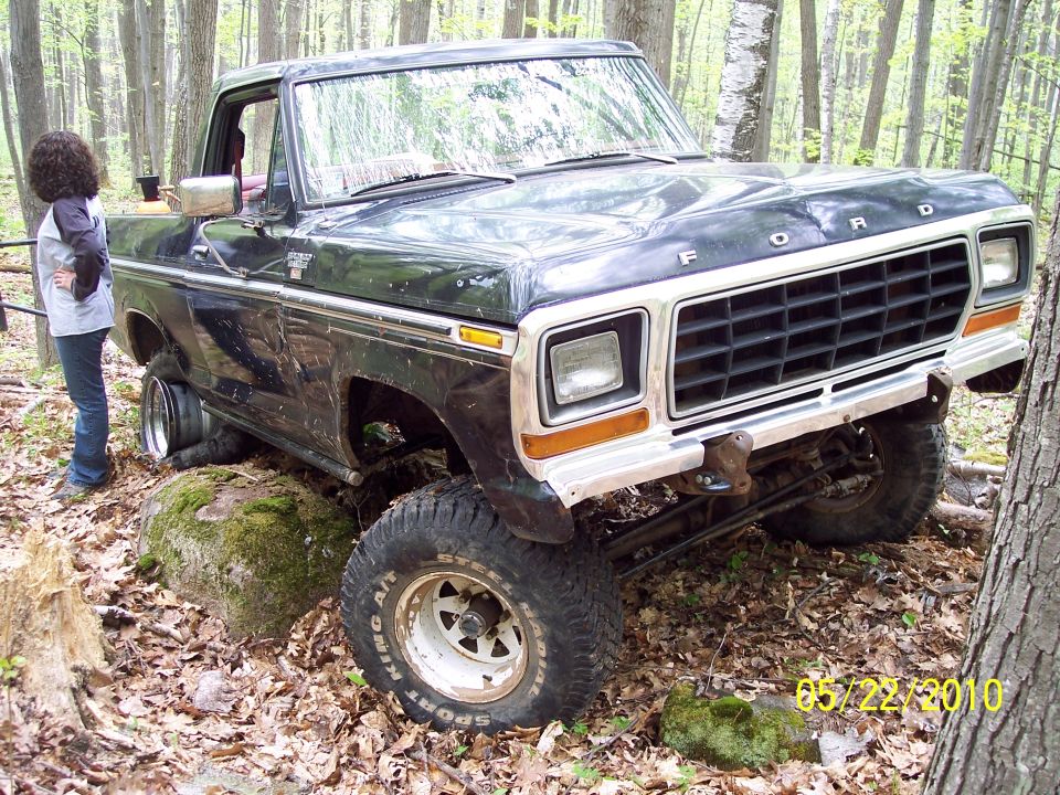 Black 1979 Ford F-Series truck with a lifted suspension, stuck on a rock, front 3/4 view