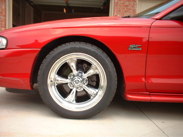 Chrome five-spoke wheel on red Mustang GT front fender with GT badge