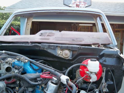 1985 Ford Bronco - The engine bay and windshield frame of a vehicle are visible, suggesting it is undergoing restoration or repair.