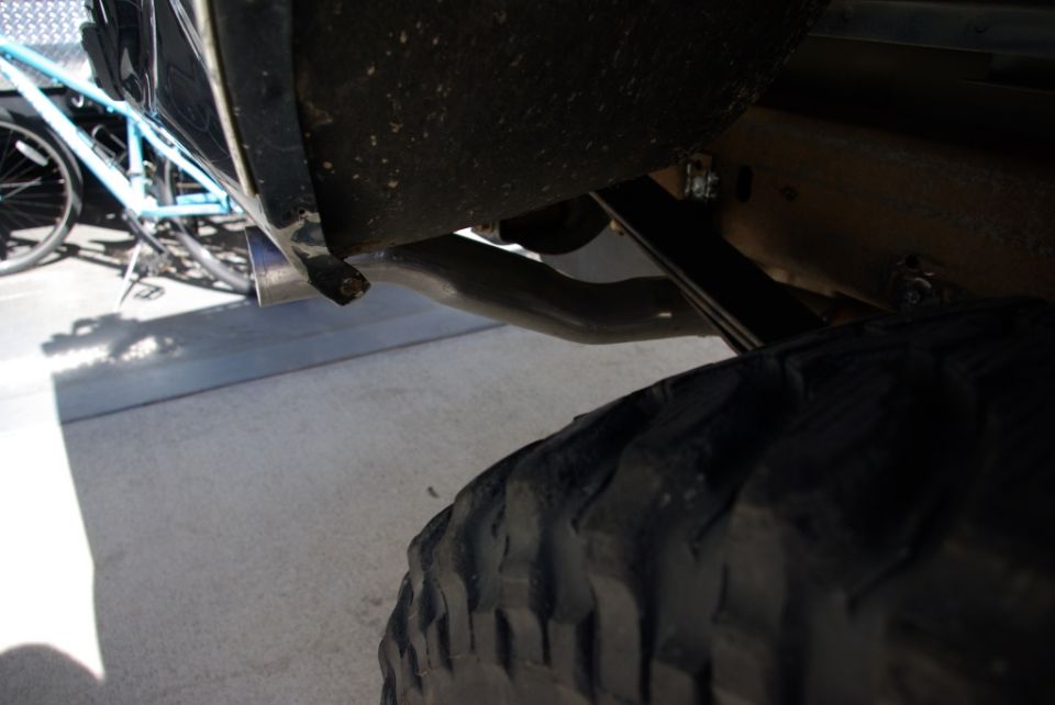 Exhaust pipe and tire of a vehicle, with a bicycle in the background