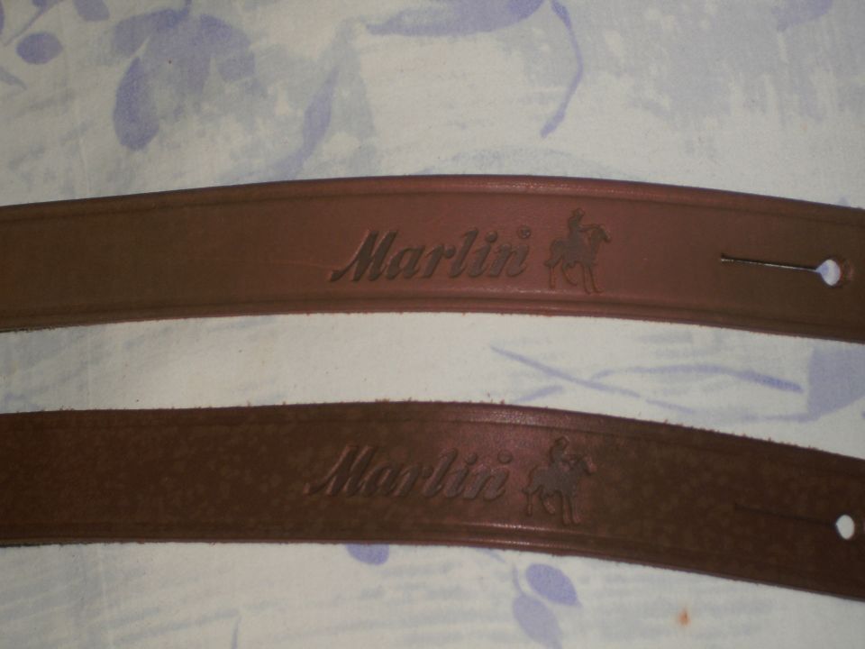 Two brown leather Marlin-branded rifle slings on floral fabric